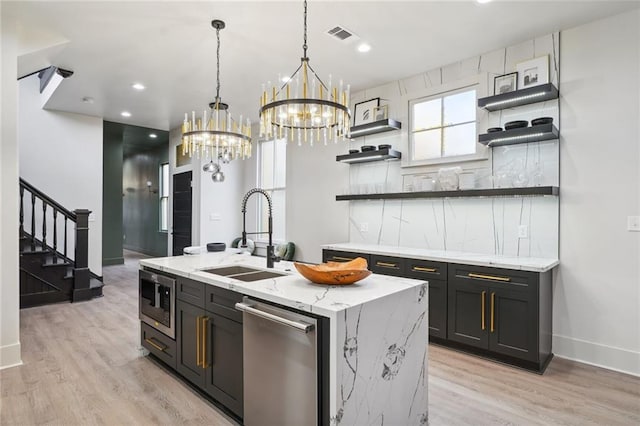 kitchen featuring stainless steel appliances, open shelves, a sink, and light wood-style flooring