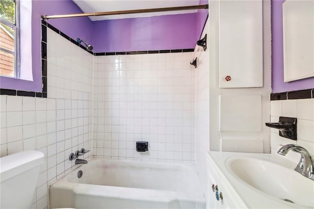 full bathroom featuring vanity, tile walls, tiled shower / bath combo, and toilet