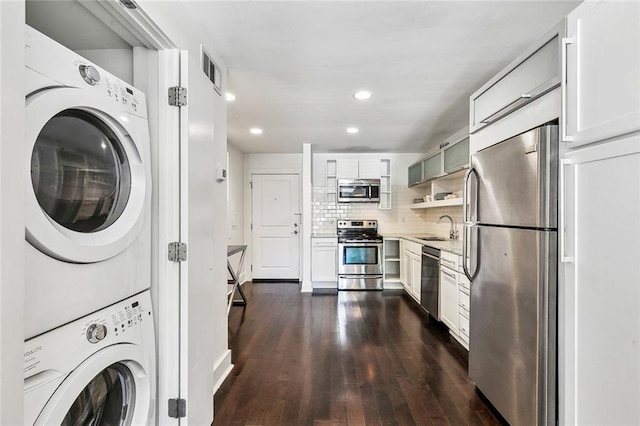 clothes washing area with sink, dark hardwood / wood-style floors, and stacked washing maching and dryer