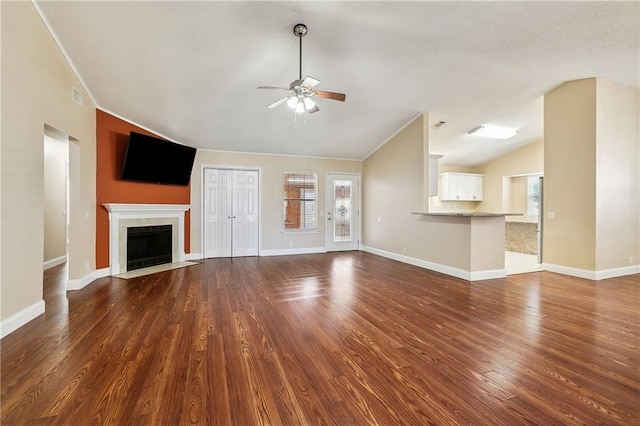 unfurnished living room with dark hardwood / wood-style floors, a tiled fireplace, vaulted ceiling, and ceiling fan