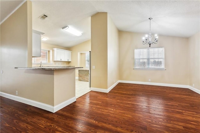 kitchen with dark hardwood / wood-style floors, vaulted ceiling, decorative light fixtures, a chandelier, and white cabinets