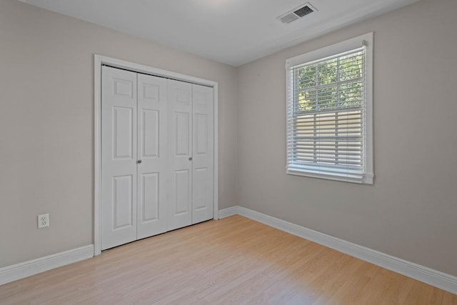 unfurnished bedroom featuring light hardwood / wood-style flooring and a closet