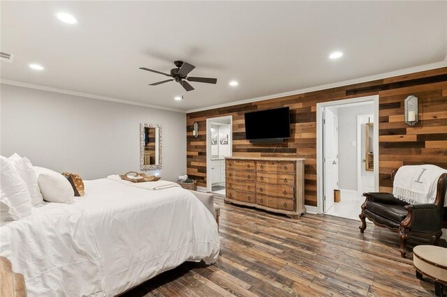 bedroom with wood walls, connected bathroom, dark wood-type flooring, and ceiling fan