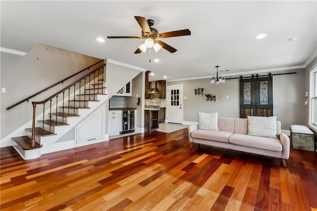 living room featuring crown molding, a barn door, hardwood / wood-style flooring, and ceiling fan