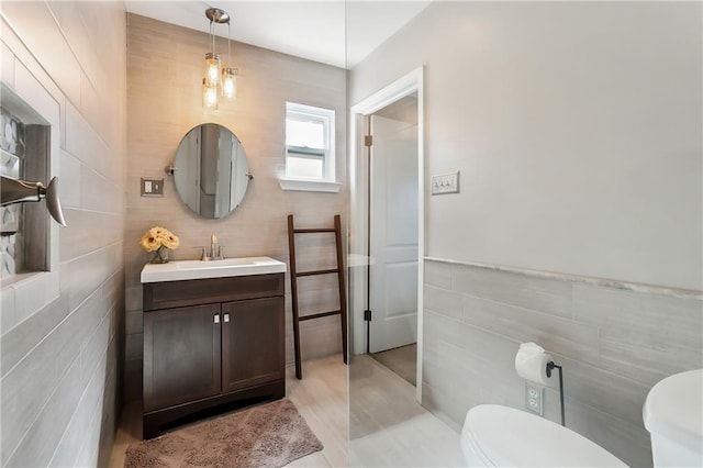 bathroom with toilet, vanity, and tile walls