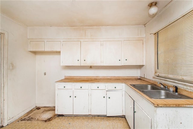 kitchen with ornamental molding, sink, and white cabinets