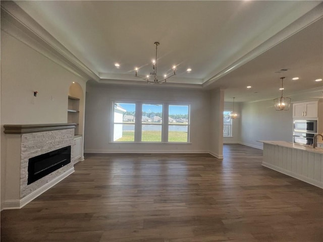 unfurnished living room featuring crown molding, dark hardwood / wood-style flooring, a fireplace, and built in shelves