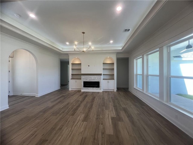 7049 Bald Eagle Cir, Madisonville, LA 70447 - unfurnished living room with an inviting chandelier, built in features, a raised ceiling, baseboards, and dark wood-style flooring