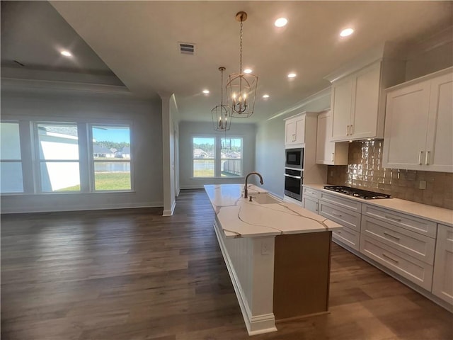 kitchen with dark wood-type flooring, appliances with stainless steel finishes, decorative light fixtures, and white cabinets