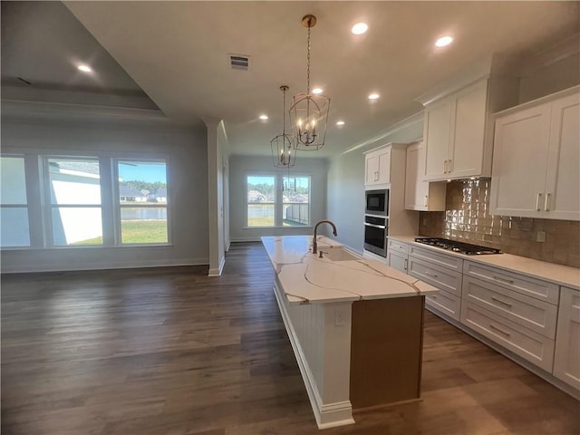 7049 Bald Eagle Cir, Madisonville, LA 70447 - kitchen featuring a center island with sink, backsplash, baseboards, appliances with stainless steel finishes, and visible vents