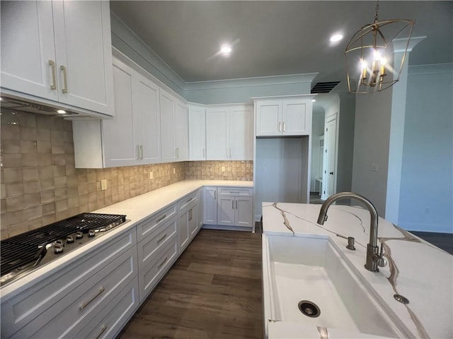 kitchen featuring white cabinetry, light stone countertops, ornamental molding, dark wood-type flooring, and sink