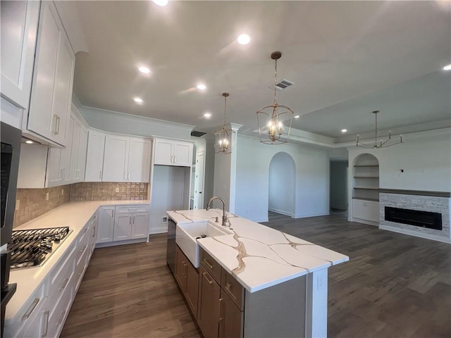 kitchen with white cabinets, dark wood-type flooring, sink, and a kitchen island with sink