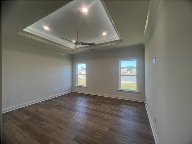 unfurnished room featuring a tray ceiling, dark wood-type flooring, and ceiling fan