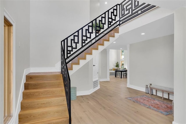 stairway featuring a towering ceiling and hardwood / wood-style flooring