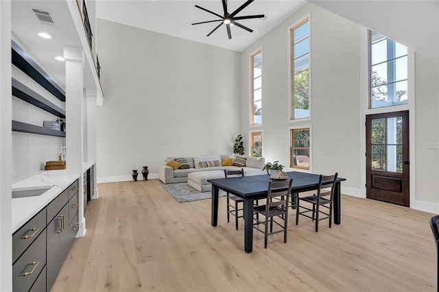 dining area featuring light hardwood / wood-style floors, a towering ceiling, sink, and ceiling fan