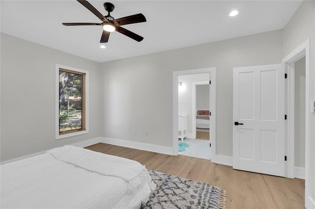 bedroom with connected bathroom, light wood-type flooring, and ceiling fan