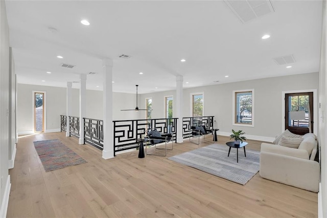 living room featuring light hardwood / wood-style floors, decorative columns, a wealth of natural light, and ceiling fan