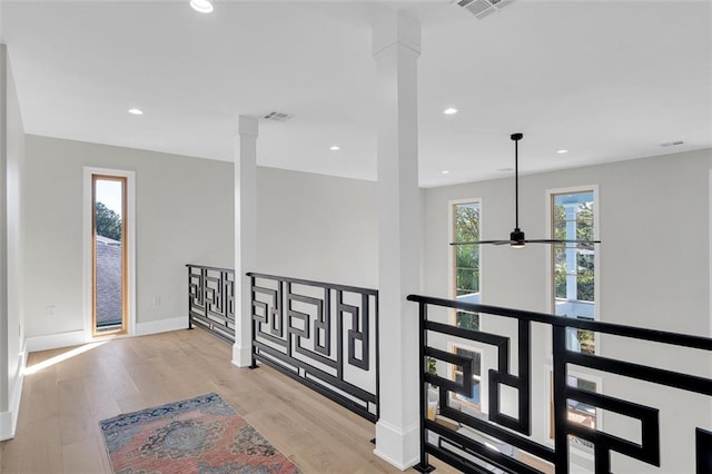 hallway featuring ornate columns and light wood-type flooring