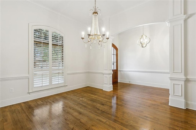 unfurnished dining area with ornamental molding, decorative columns, dark hardwood / wood-style floors, and an inviting chandelier