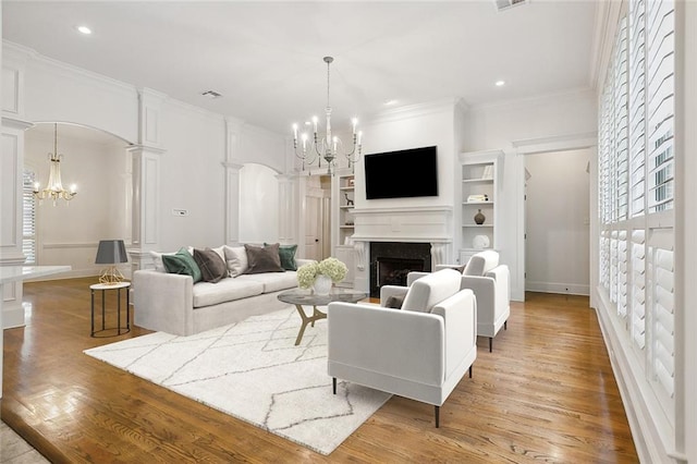 living room featuring ornamental molding, decorative columns, light hardwood / wood-style flooring, and a notable chandelier