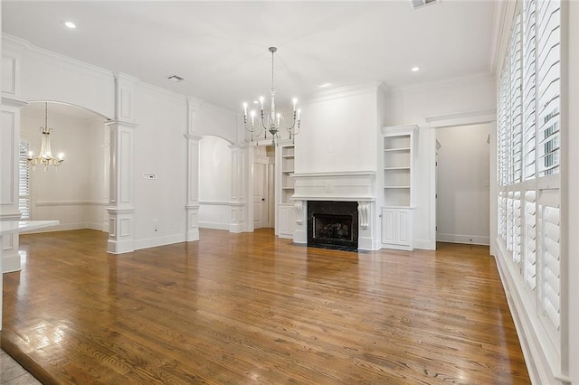 unfurnished living room featuring ornamental molding, decorative columns, a premium fireplace, and wood-type flooring