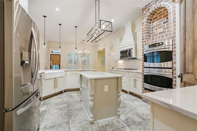 kitchen featuring light stone countertops, a center island, white cabinetry, stainless steel appliances, and pendant lighting