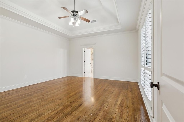 unfurnished room featuring dark wood-type flooring, crown molding, a tray ceiling, and ceiling fan