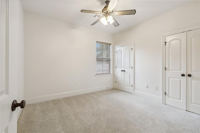 unfurnished bedroom featuring light carpet, multiple closets, and ceiling fan