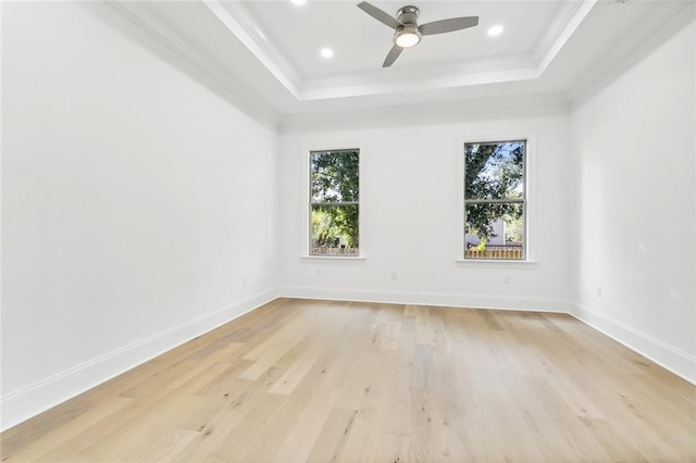 empty room featuring a wealth of natural light, ornamental molding, light hardwood / wood-style flooring, and a raised ceiling