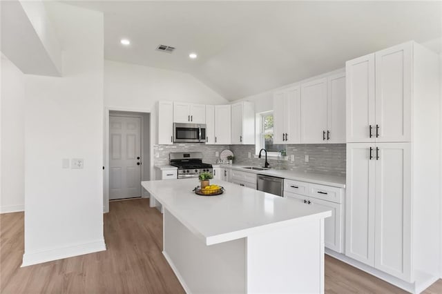 kitchen featuring stainless steel appliances, light wood-type flooring, a kitchen island, and white cabinets