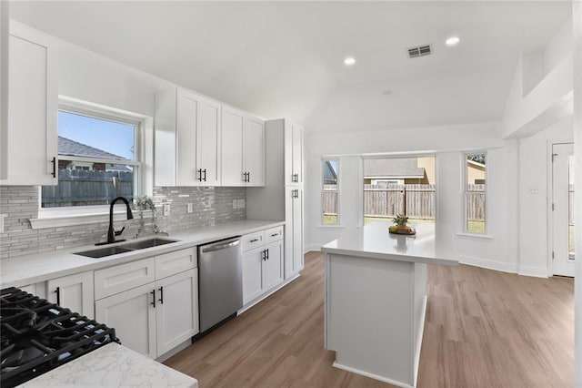 kitchen with light hardwood / wood-style flooring, lofted ceiling, dishwasher, and white cabinets