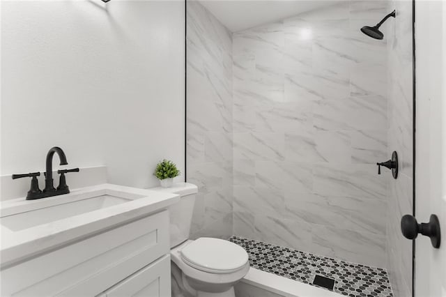 bathroom featuring vanity, tiled shower, and toilet