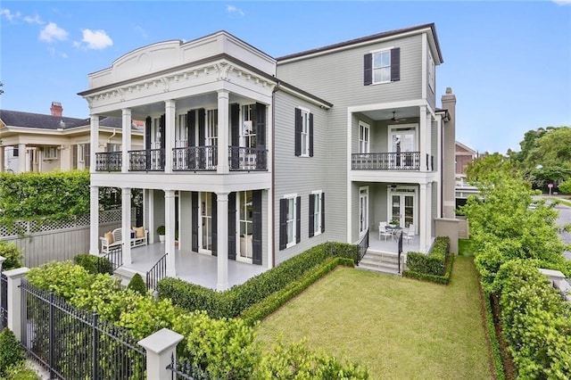 rear view of property with a lawn, a balcony, and french doors