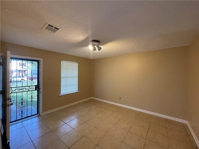 empty room featuring a textured ceiling and light tile patterned floors