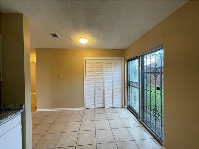 unfurnished bedroom with a textured ceiling, a closet, and light tile patterned floors