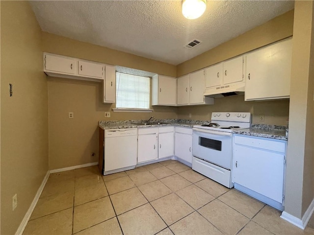 kitchen with white appliances, a textured ceiling, white cabinetry, and light tile patterned floors