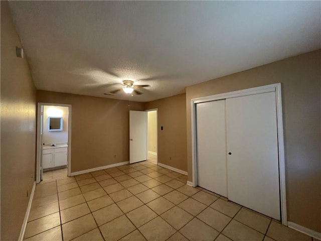 unfurnished bedroom with a closet, light tile patterned floors, ensuite bathroom, a textured ceiling, and ceiling fan