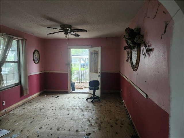 unfurnished office with ceiling fan and a textured ceiling