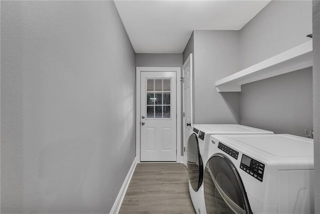 clothes washing area with light hardwood / wood-style flooring and washer and dryer