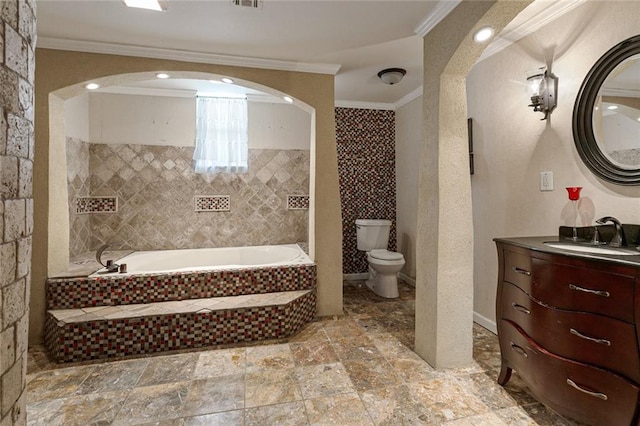 bathroom with tiled tub, crown molding, vanity, and toilet