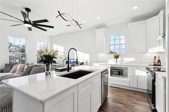 kitchen featuring appliances with stainless steel finishes, sink, white cabinetry, dark wood-type flooring, and a center island with sink