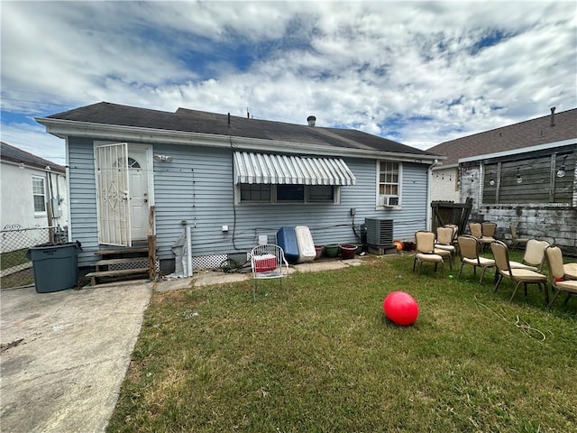 rear view of property featuring a yard, cooling unit, and central air condition unit