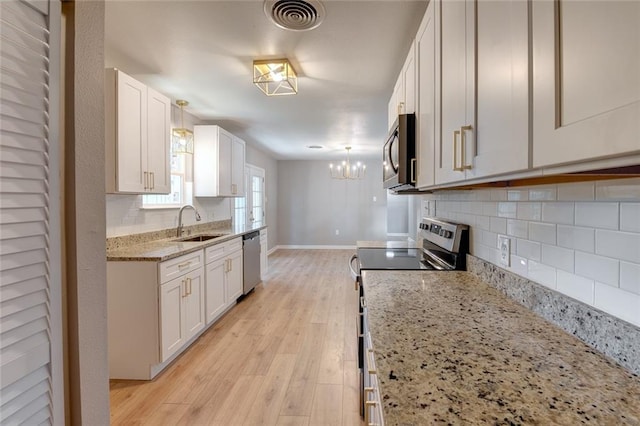 kitchen featuring light hardwood / wood-style floors, appliances with stainless steel finishes, hanging light fixtures, and white cabinets