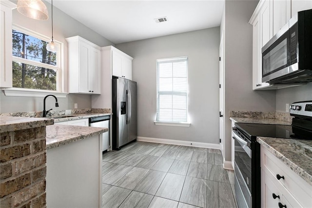 kitchen featuring hanging light fixtures, light stone counters, white cabinetry, sink, and stainless steel appliances