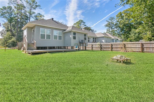 rear view of house featuring a wooden deck and a lawn