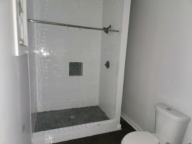 bathroom with toilet and a tile shower