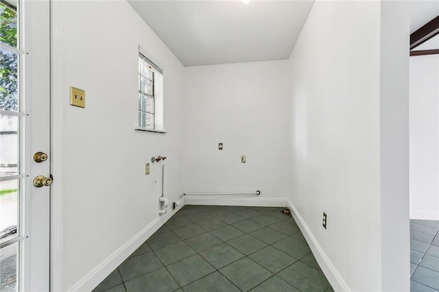 laundry area with electric dryer hookup and dark tile patterned flooring