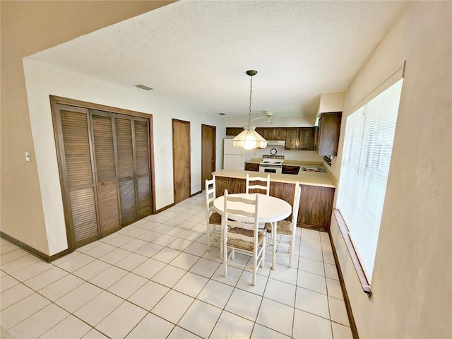 kitchen with baseboard heating, a kitchen breakfast bar, kitchen peninsula, decorative light fixtures, and white appliances