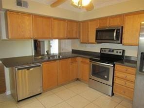 kitchen featuring light tile patterned floors, stainless steel appliances, sink, and ceiling fan