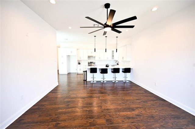 unfurnished living room with ceiling fan, sink, and dark hardwood / wood-style floors